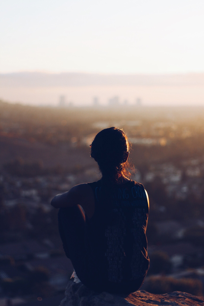 femme de dos regardant une ville à l'horizon